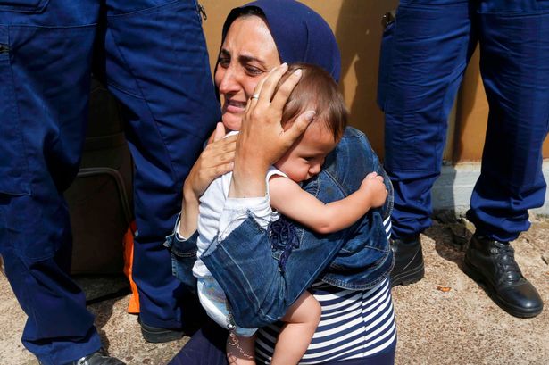 Hungarian policemen stand by a migrant holding a baby at the railway station in the town of Bicske Hungary